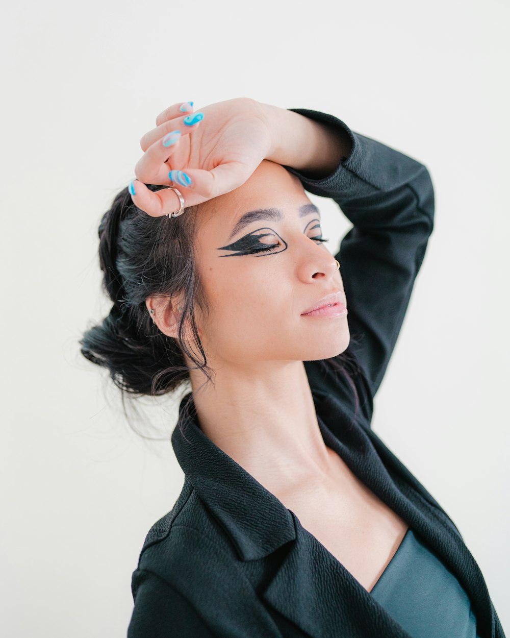 a woman in a black jacket is holding her hand up to her head