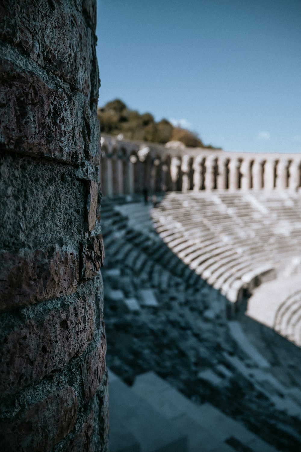 a stone wall with a row of seats in the background