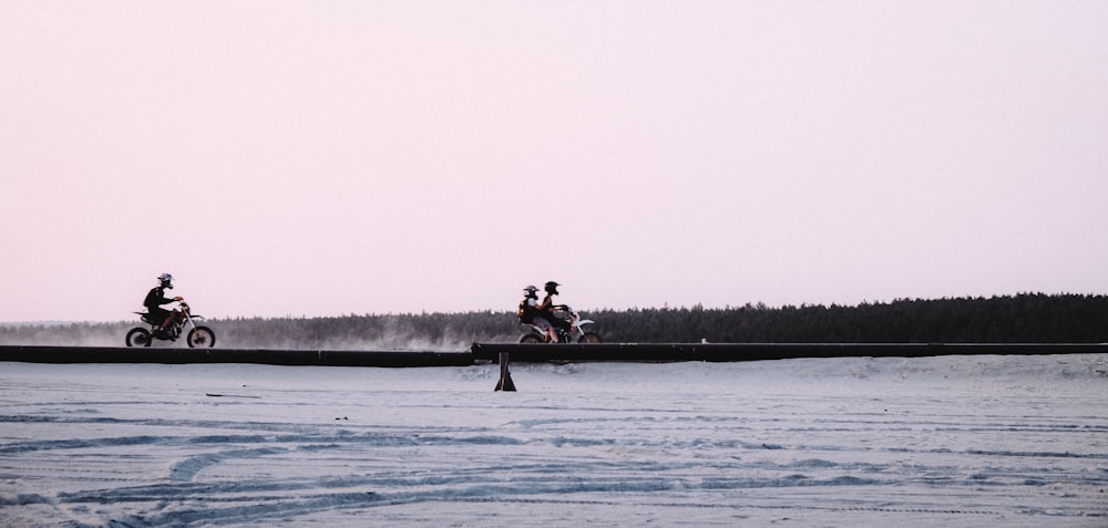 two people riding motorcycles on a snowy surface