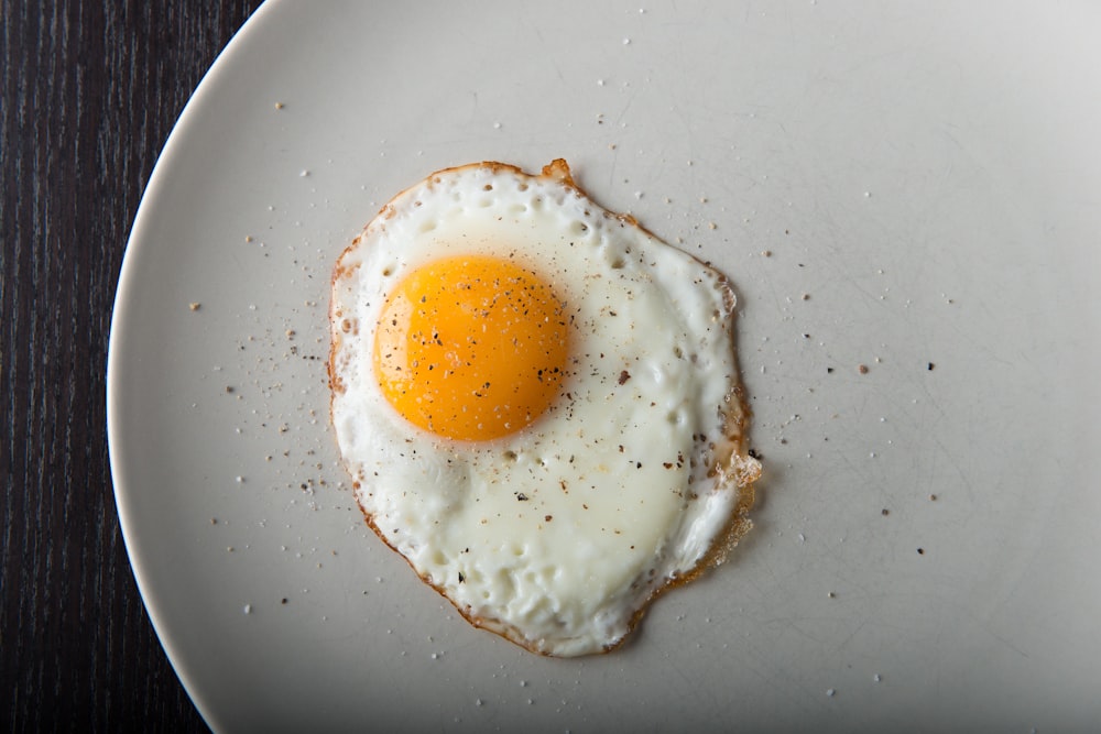 a fried egg on a white plate on a wooden table