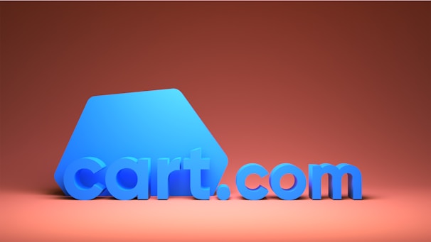 A stylized 3D rendition of the text 'cart.com' in bold blue letters. The background is a warm gradient from dark to light orange, creating a sense of depth and contrast. The design features a minimalist and modern aesthetic, focusing on the boldness of the blue letters against the warm background.