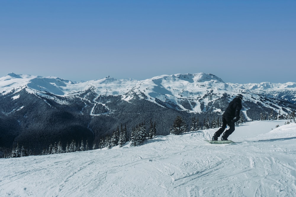 a man riding a snowboard down the side of a snow covered slope