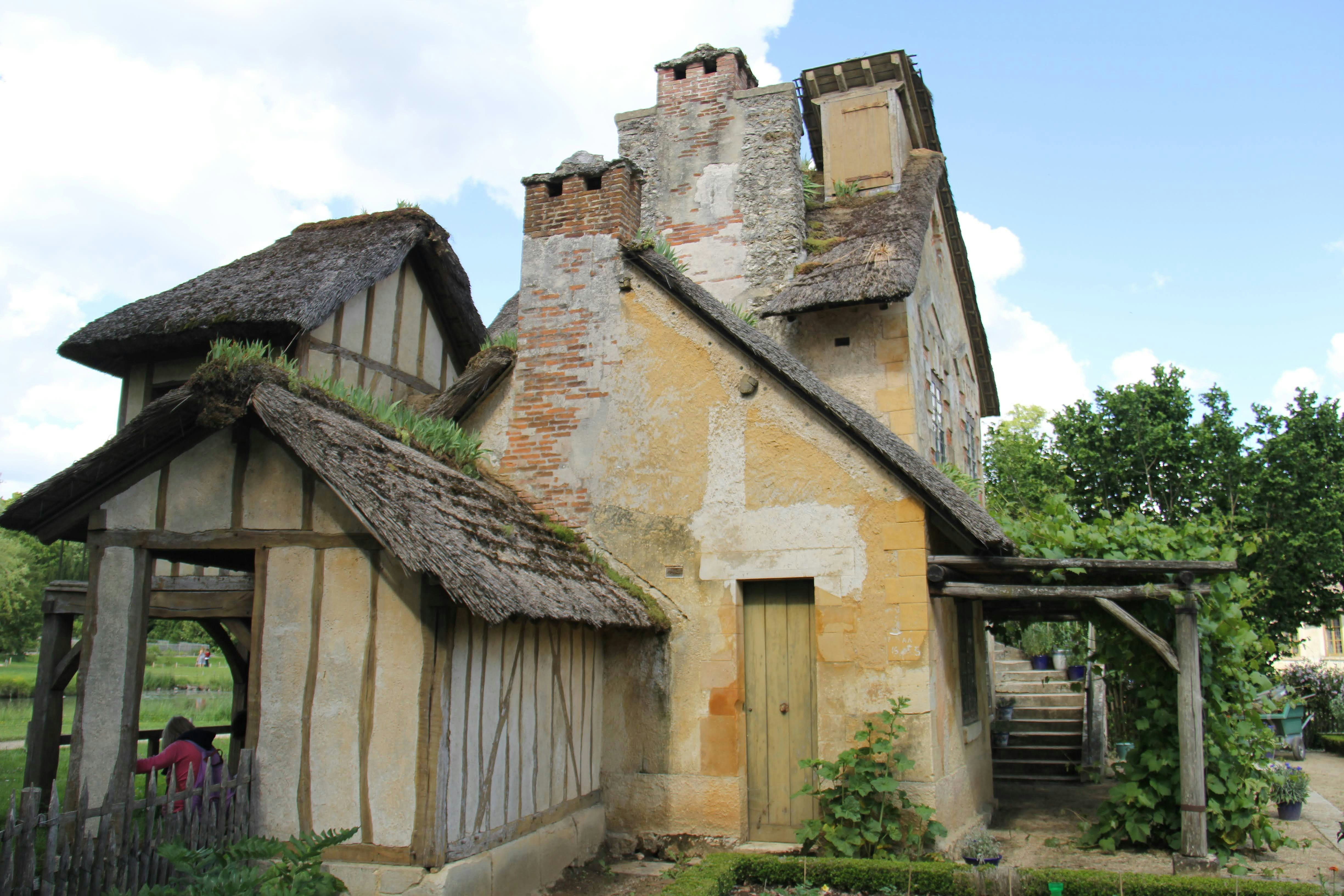 an old house with a thatched roof and a gate