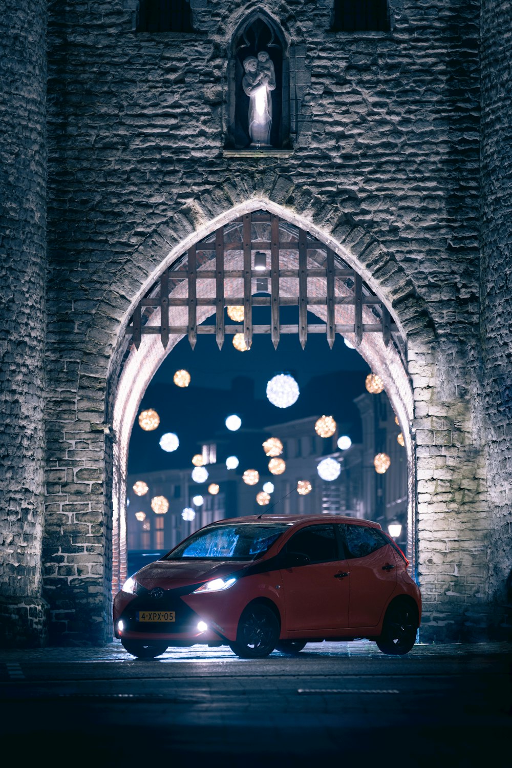 a red car parked in front of a stone building