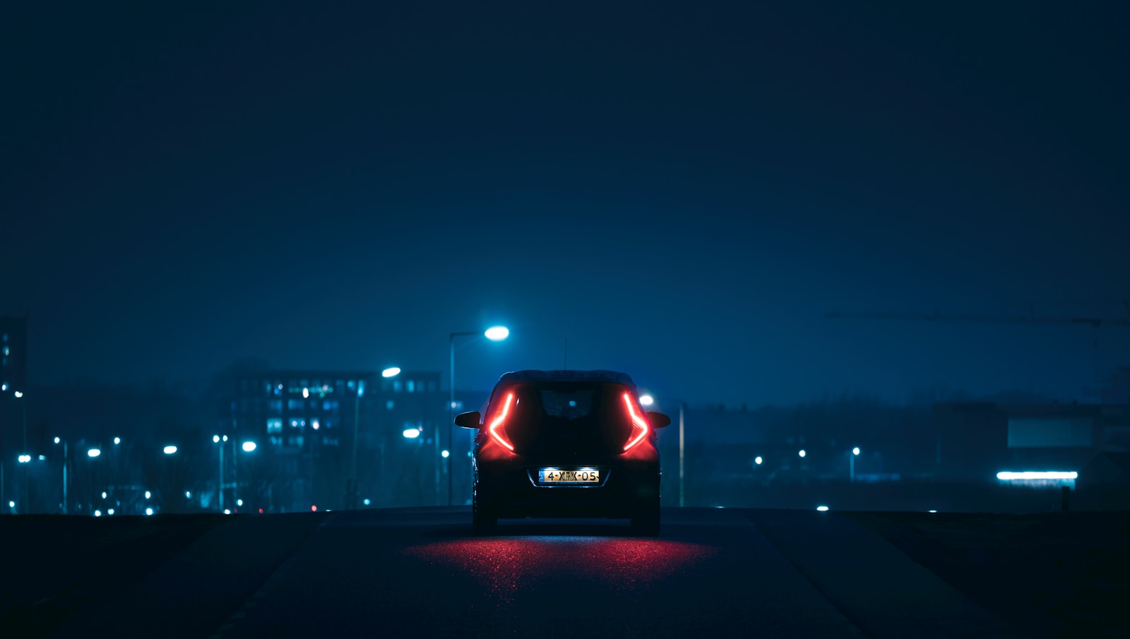 A car driving along a dark city road at night