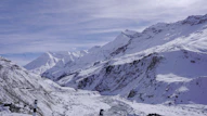 a snowy mountain range with a stream running through it