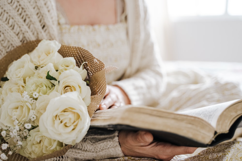 a woman holding a bouquet of flowers while reading a book