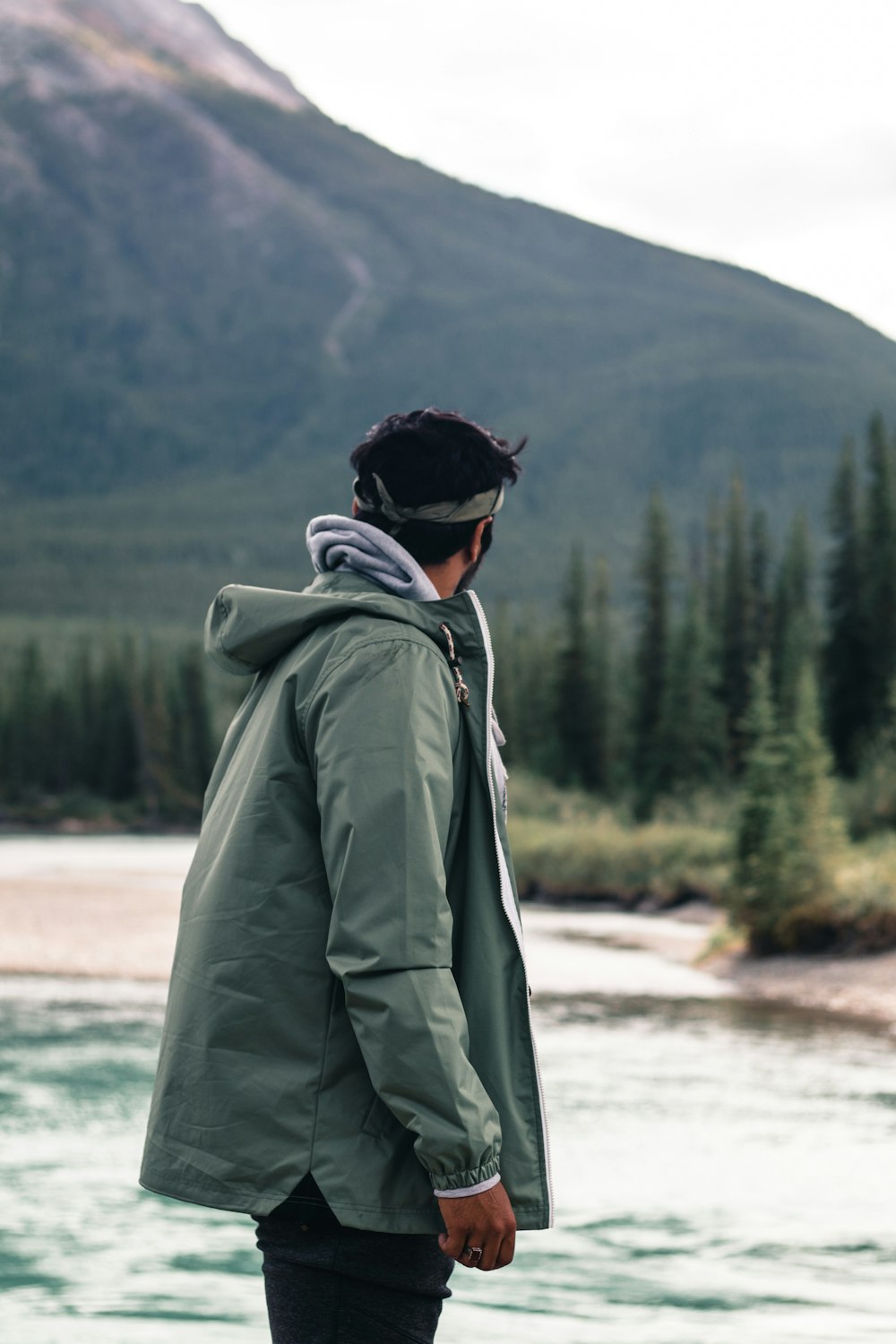 um homem em pé na frente de um lago da montanha