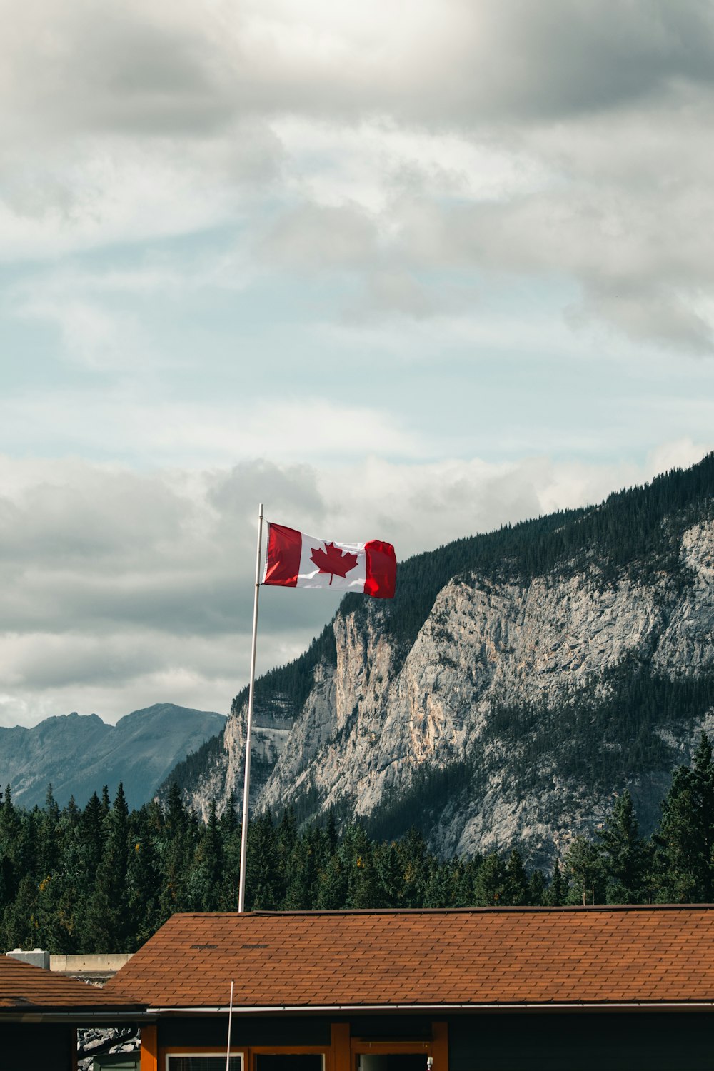 a canadian flag flying in front of a mountain