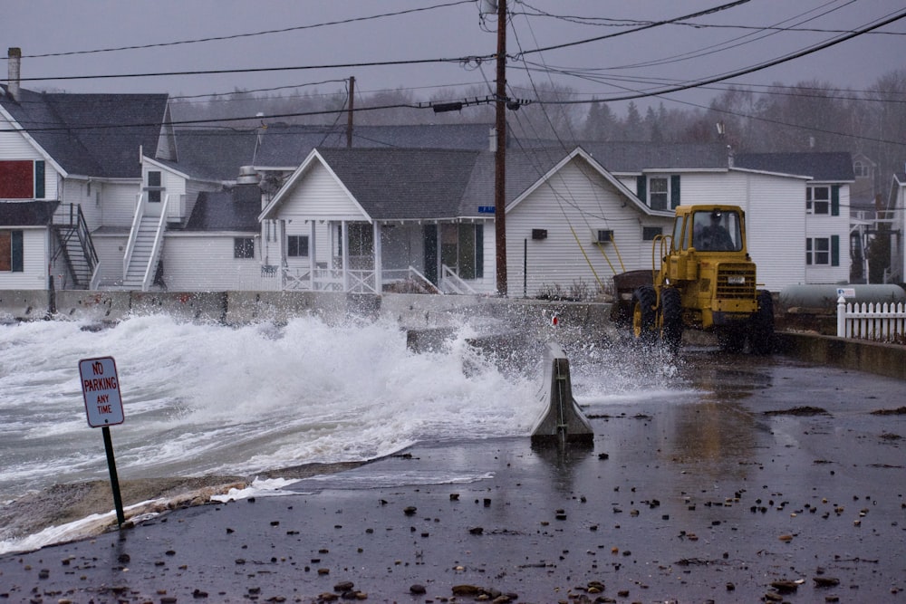 a large wave crashes into a street in front of houses