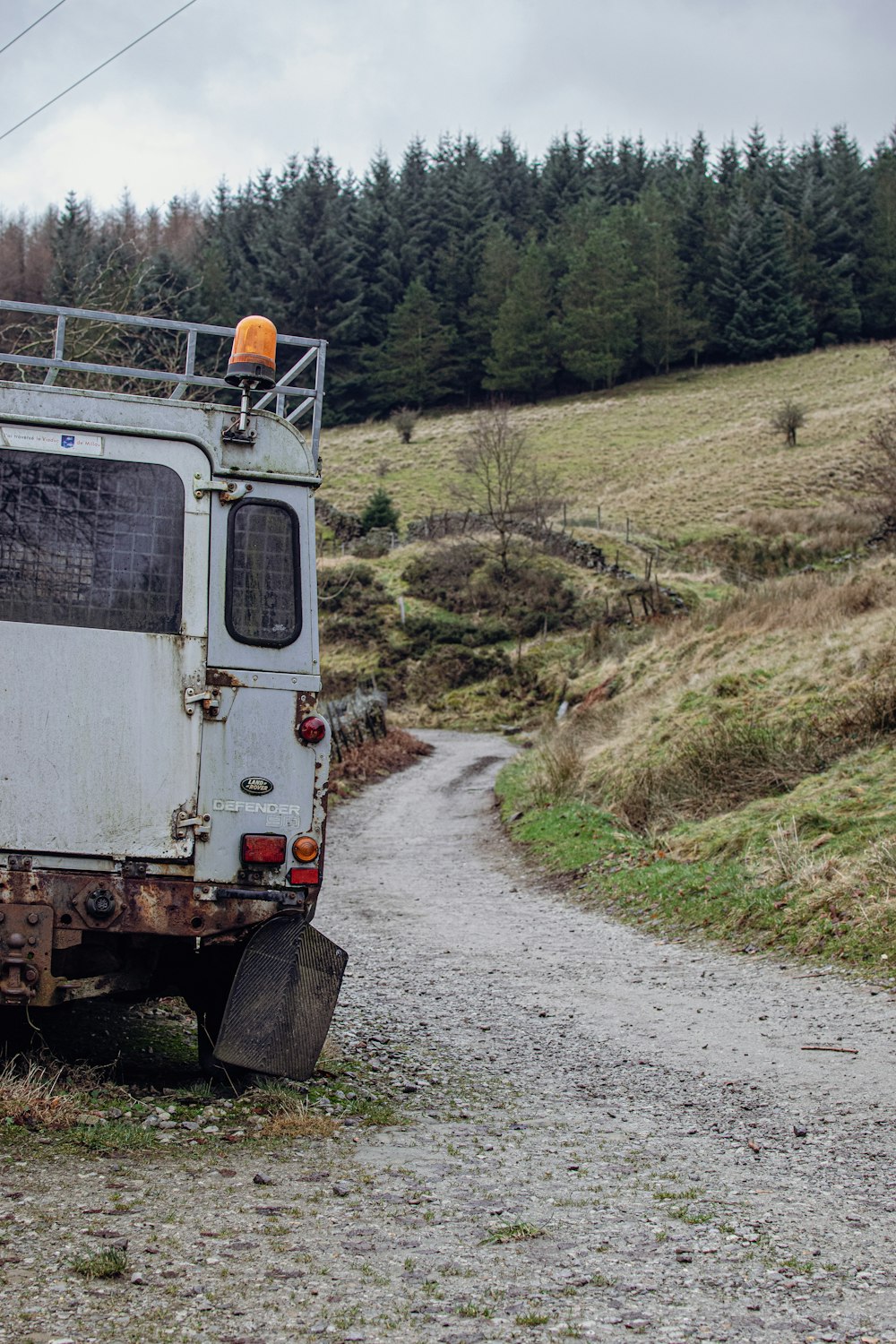 a white van parked on a dirt road next to a forest