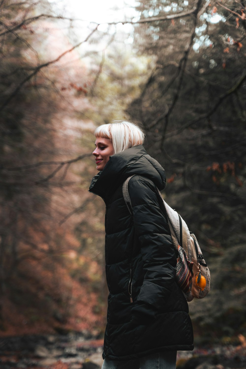 a woman with white hair is walking in the woods