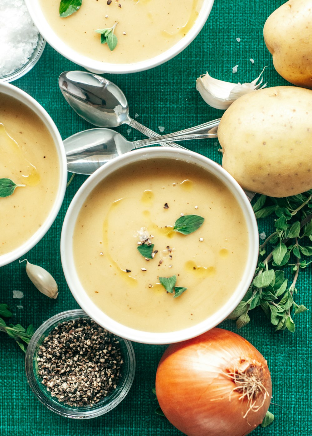 three bowls of soup on a green cloth