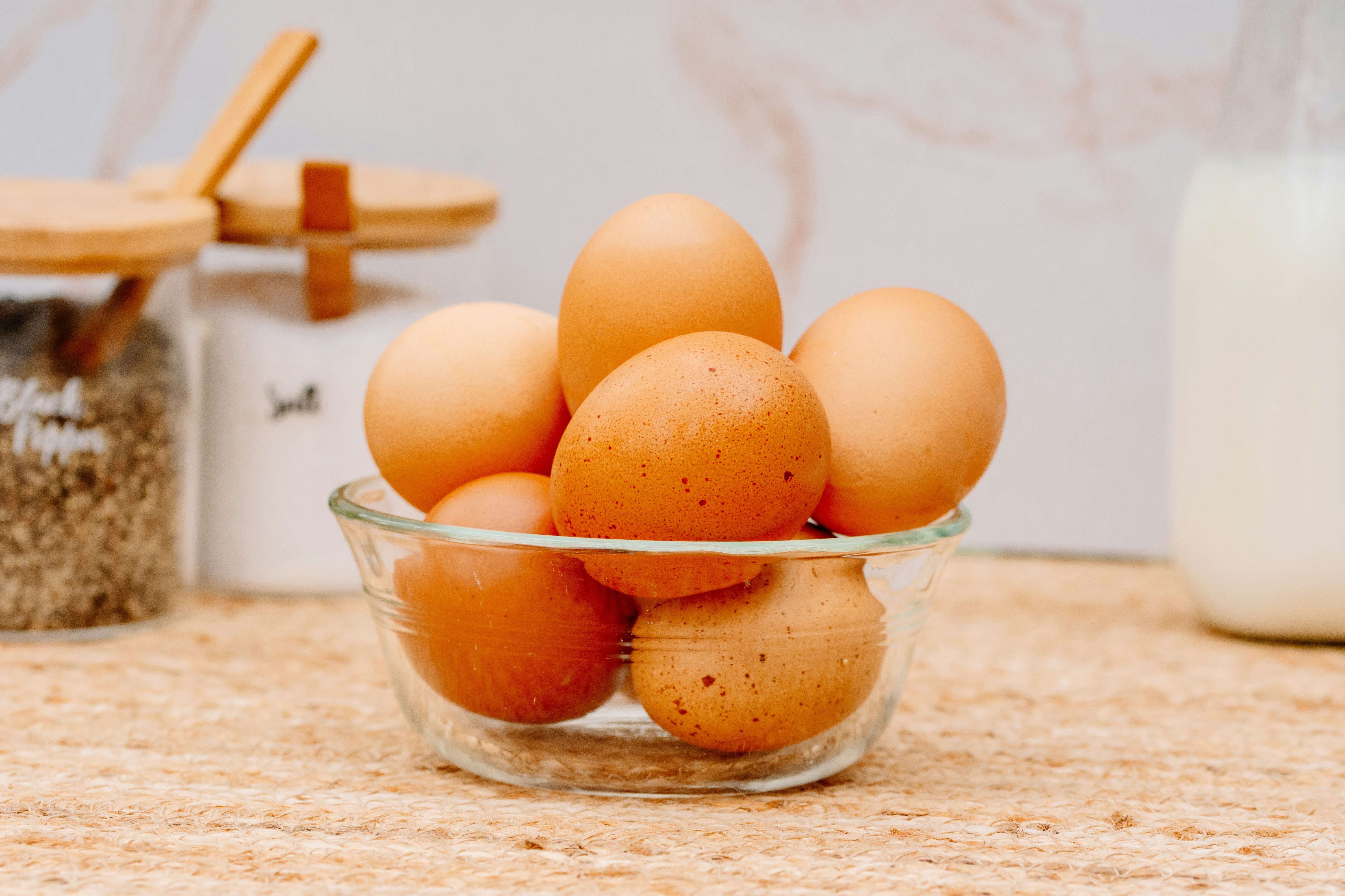 a glass bowl filled with brown eggs on top of a counter