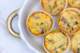 a white plate topped with mini quiches covered in cheese