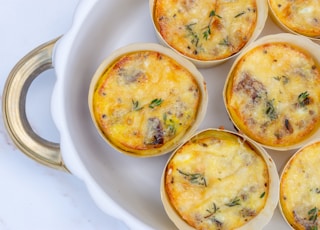 a white plate topped with mini quiches covered in cheese