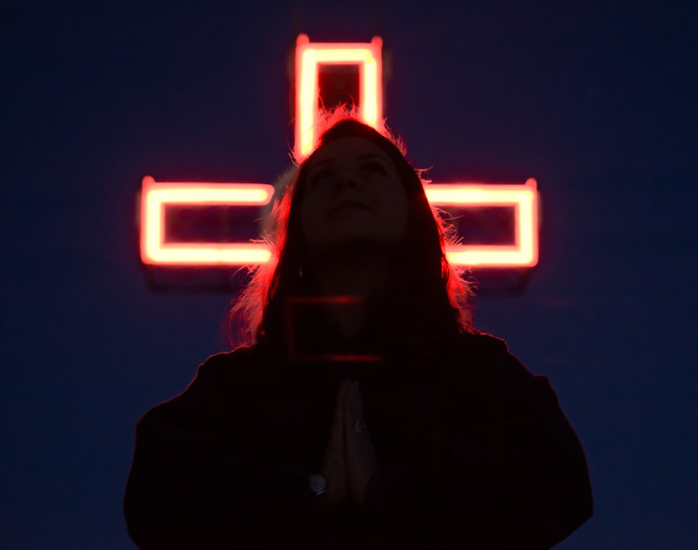 a woman standing in front of a lighted cross