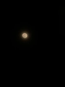 A glowing full moon casting golden light over a circle of candles and crystals.