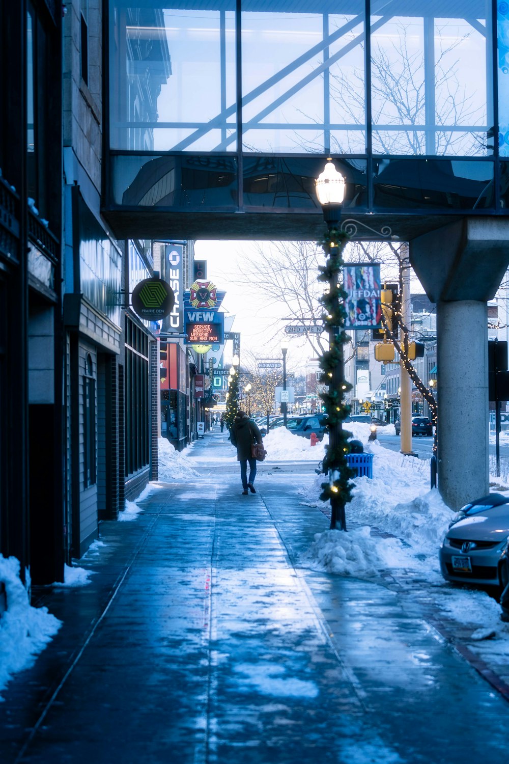 Una persona caminando por una calle nevada debajo de un puente