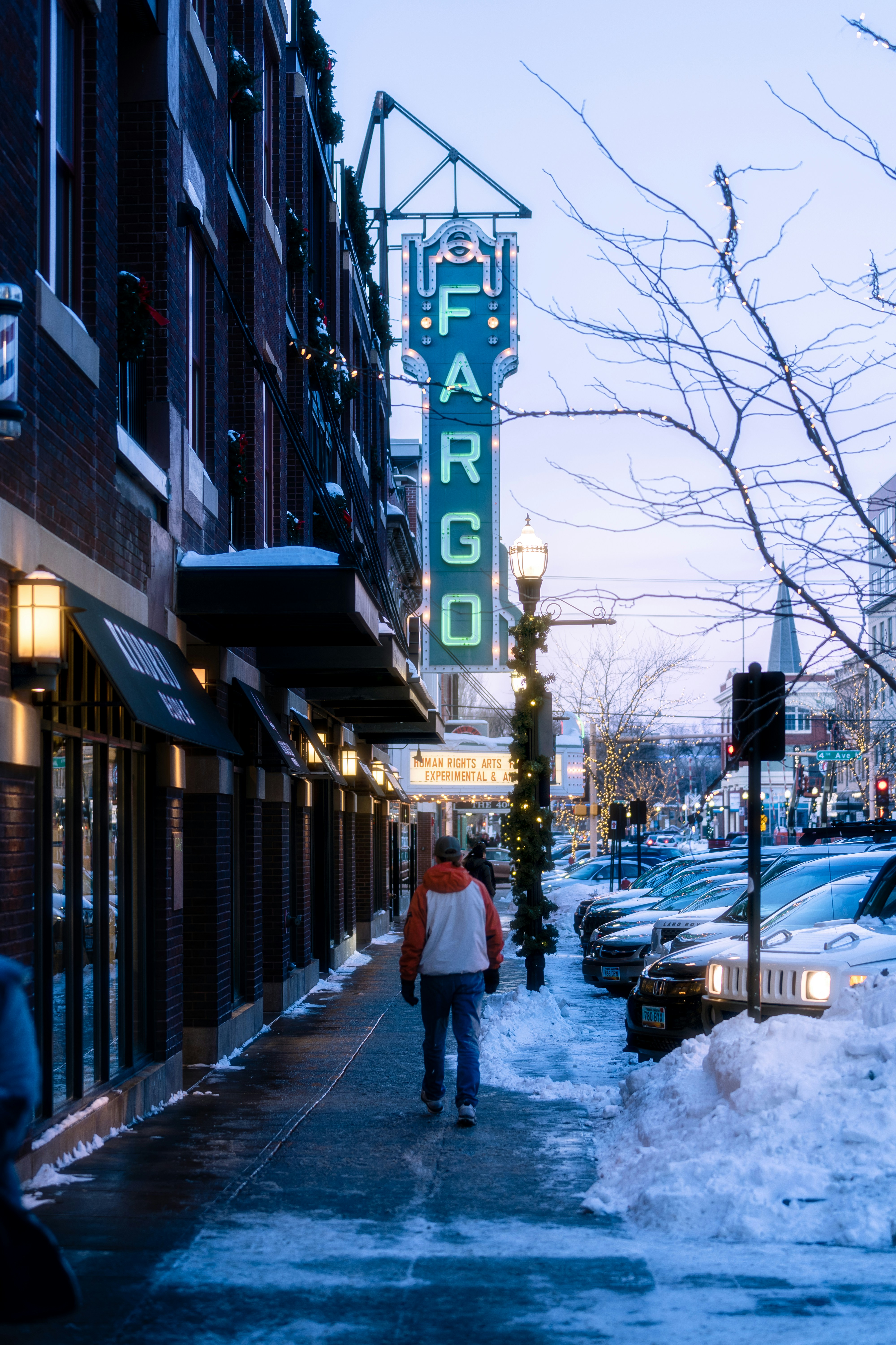 a couple of people walking down a snow covered sidewalk