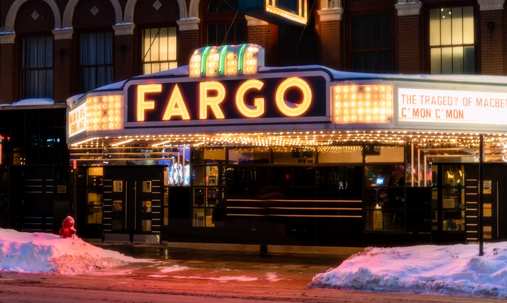 a theater marquee lit up at night with snow on the ground