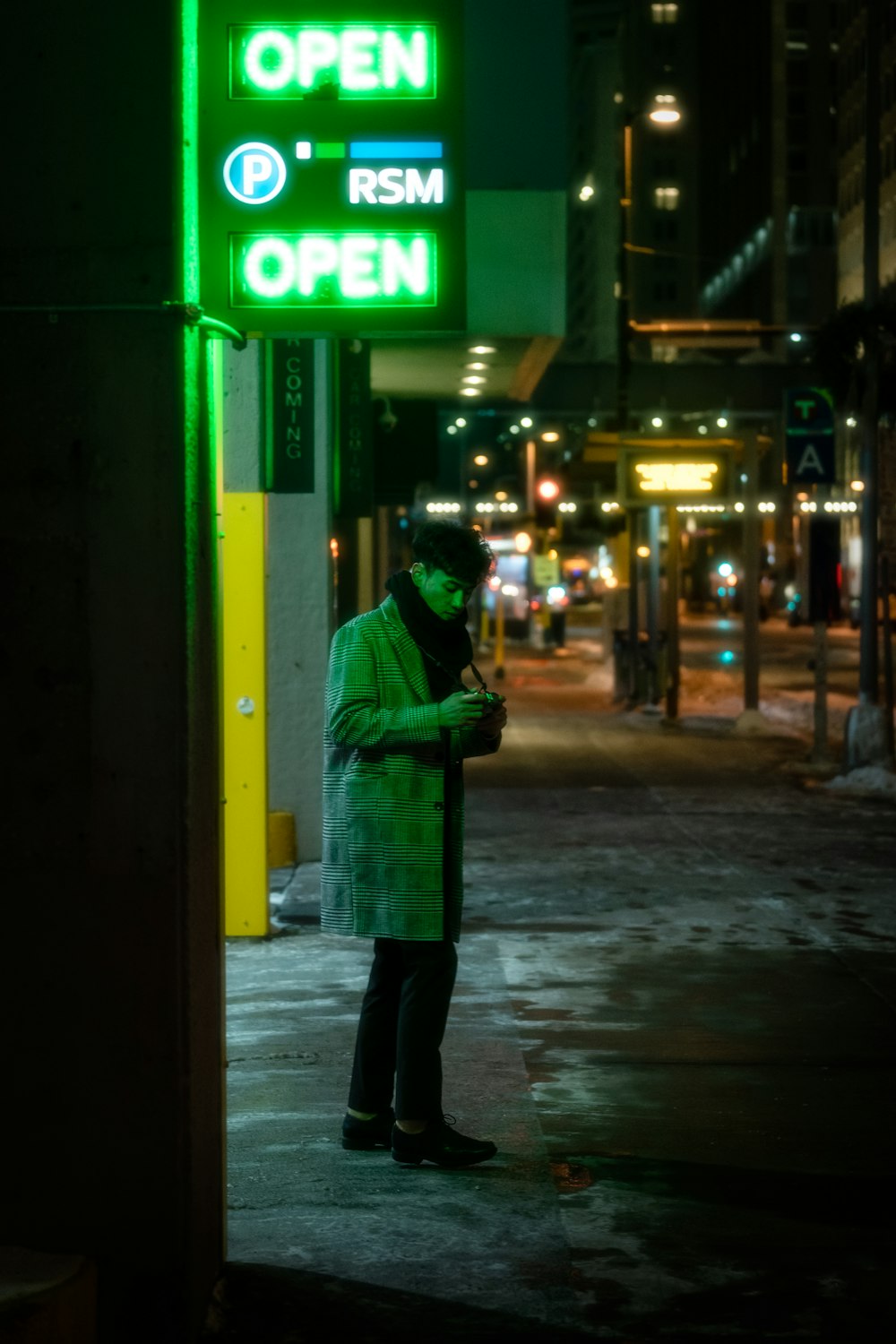 a man in a green coat is looking at his cell phone