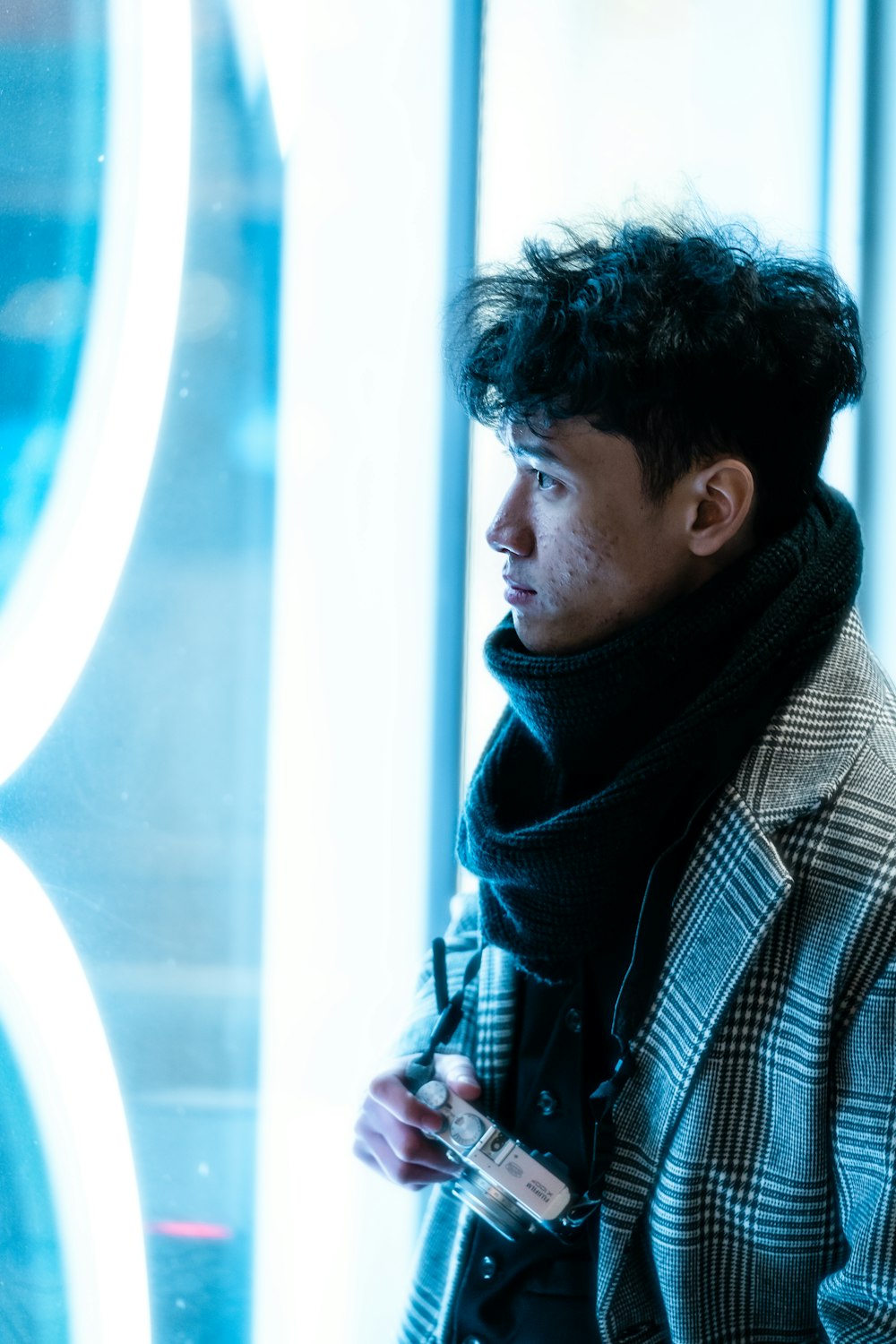 a man standing in front of a window with a scarf around his neck