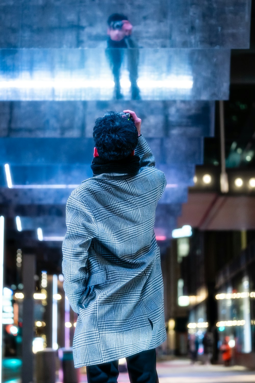 a man standing on a sidewalk in front of a billboard