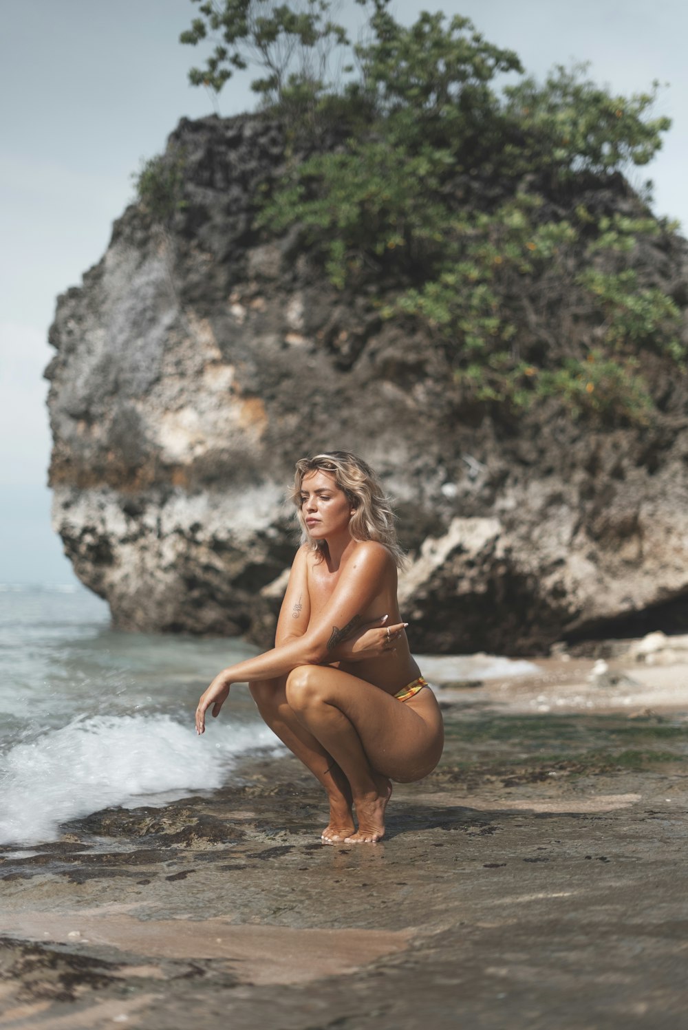 Una mujer arrodillada en una playa junto al océano