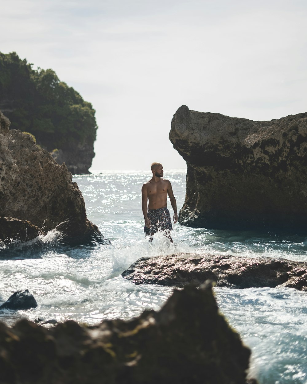 Ein Mann steht im Wasser in der Nähe von Felsen