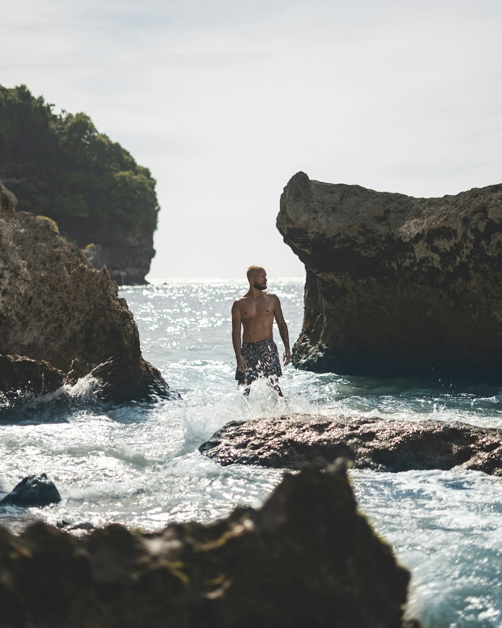 a man standing in the water near rocks