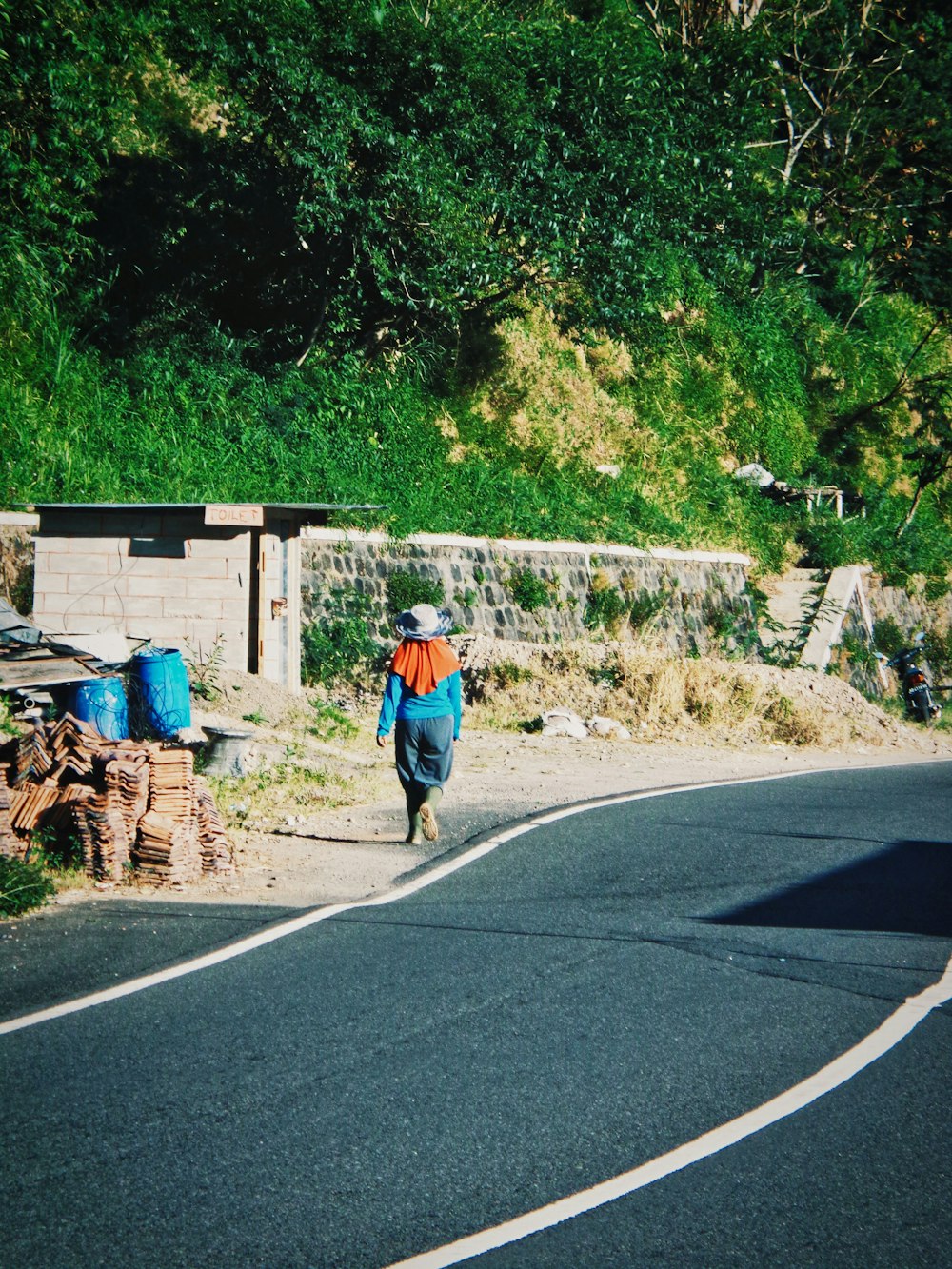 a person walking down a road next to a forest