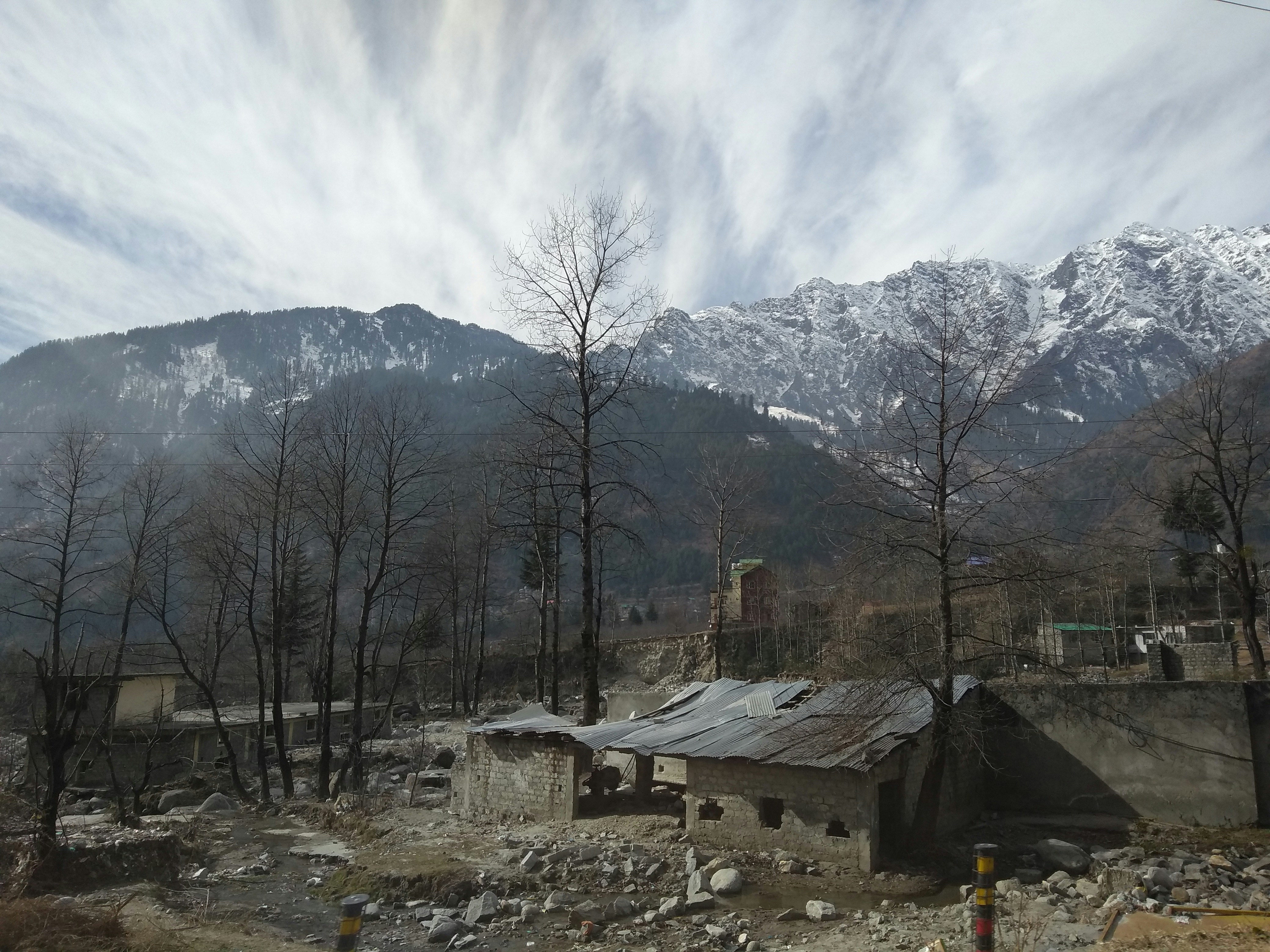 a small building in the middle of a forest with mountains in the background