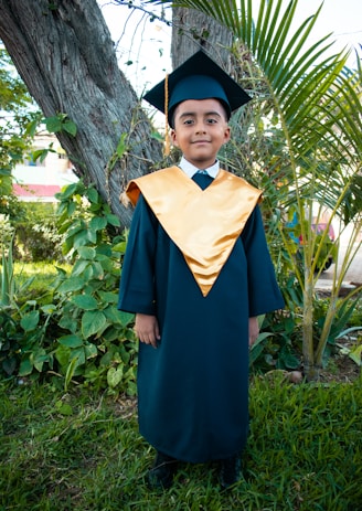 a young boy in a graduation gown and cap
