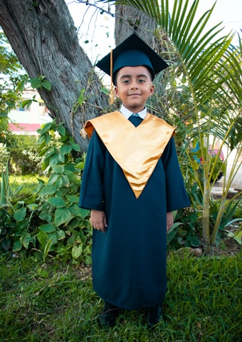 a young boy in a graduation gown and cap