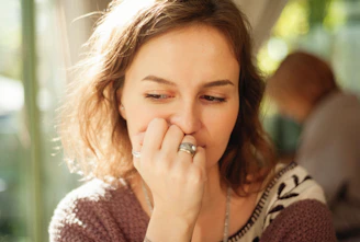 a woman holding her nose to her nose