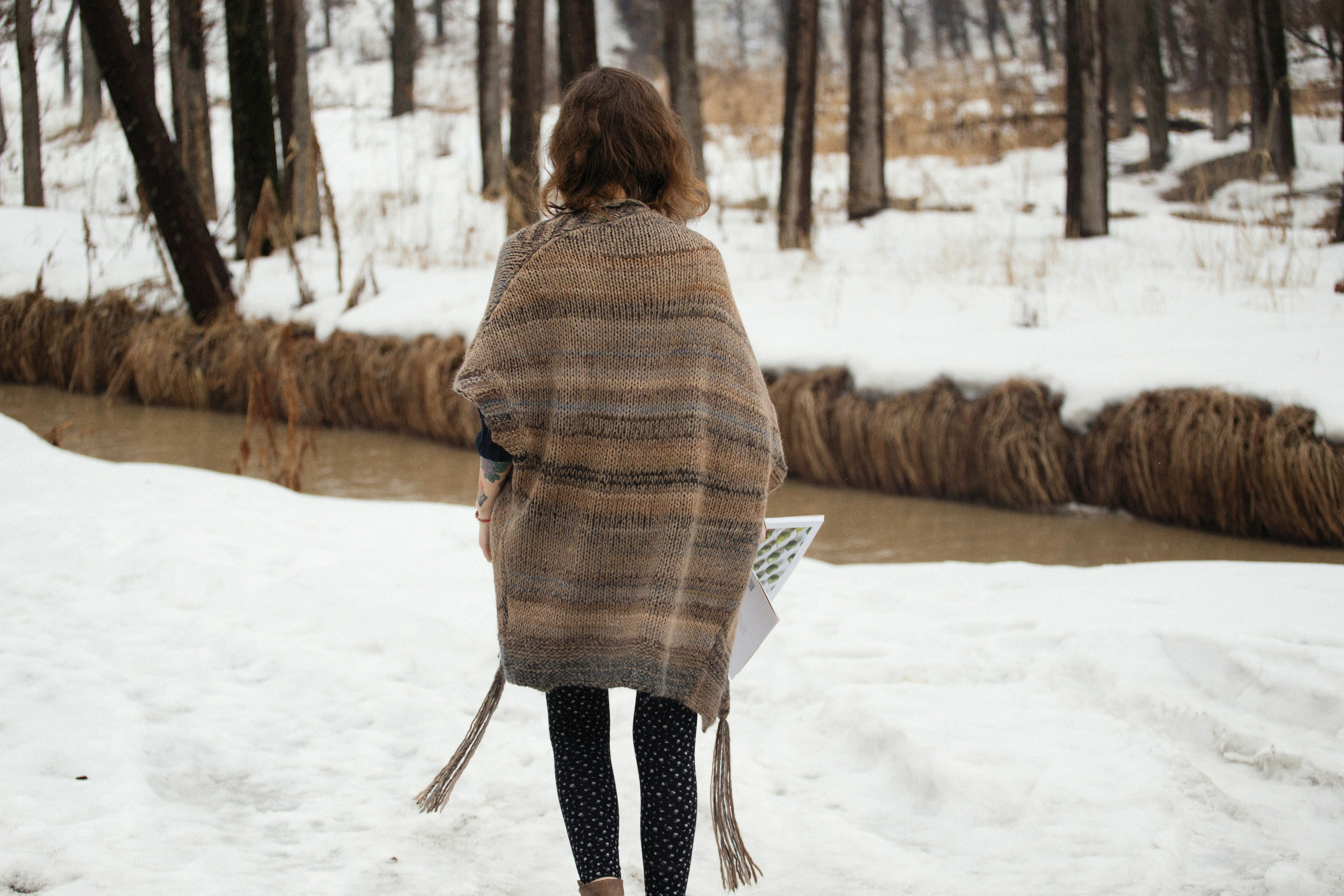 겨울철 롱패딩 관리법 - a woman walking in the snow with a blanket over her