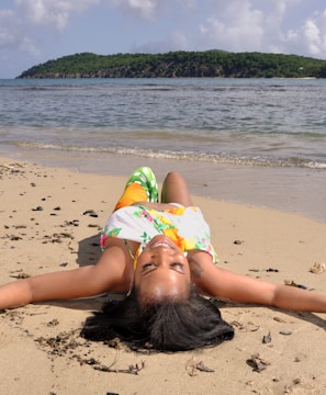 a woman laying on the beach with her head in the sand