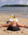 a woman laying on the beach with her head in the sand