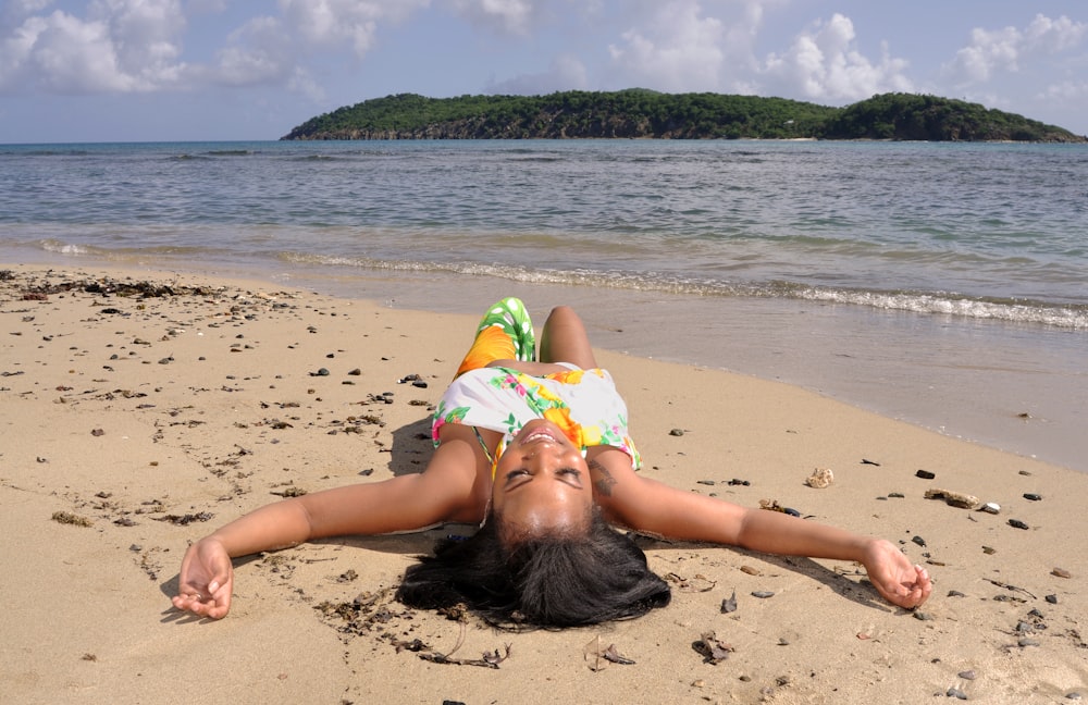 a woman laying on the beach with her head in the sand