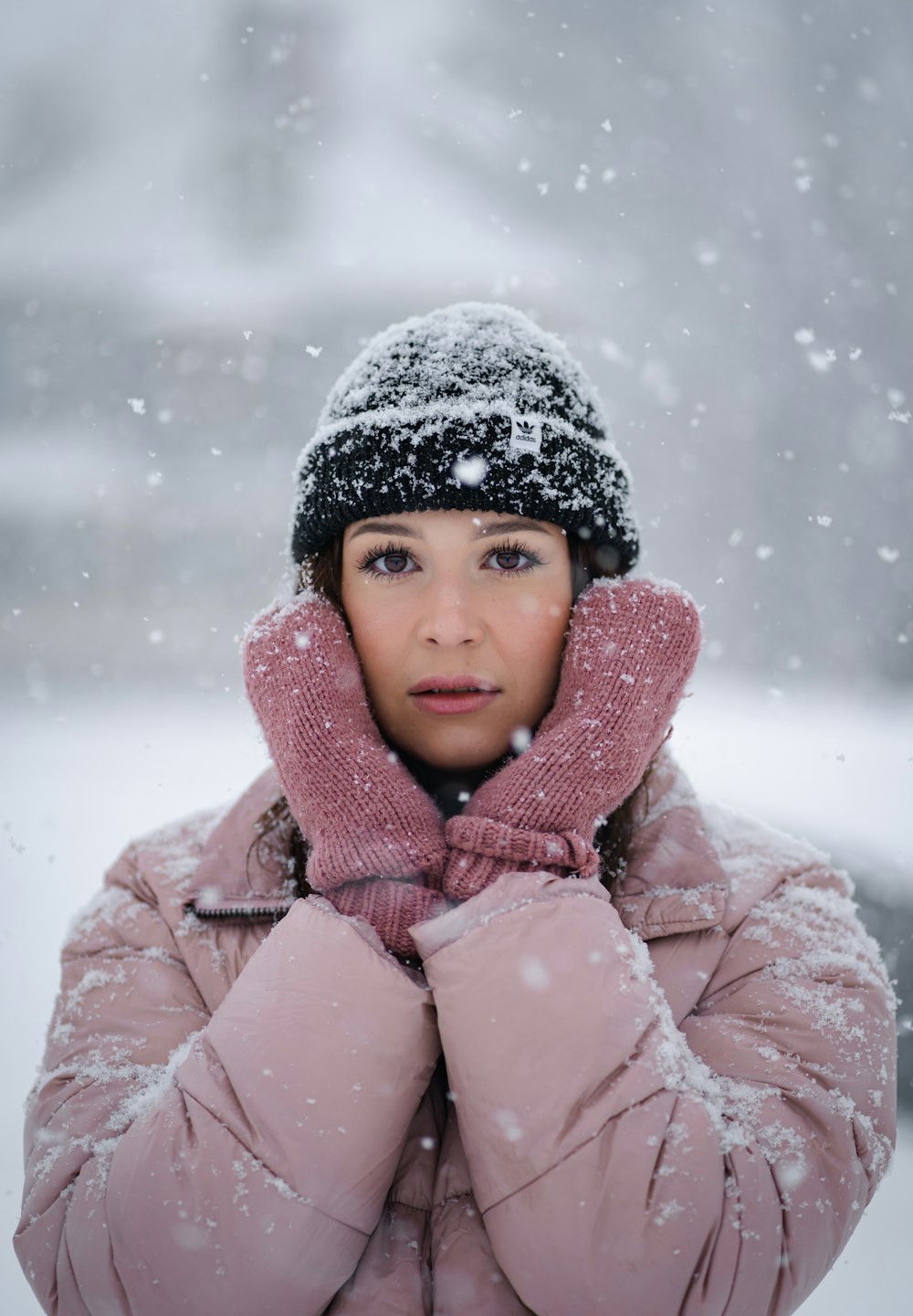 a woman wearing a pink coat and a black hat in the snow