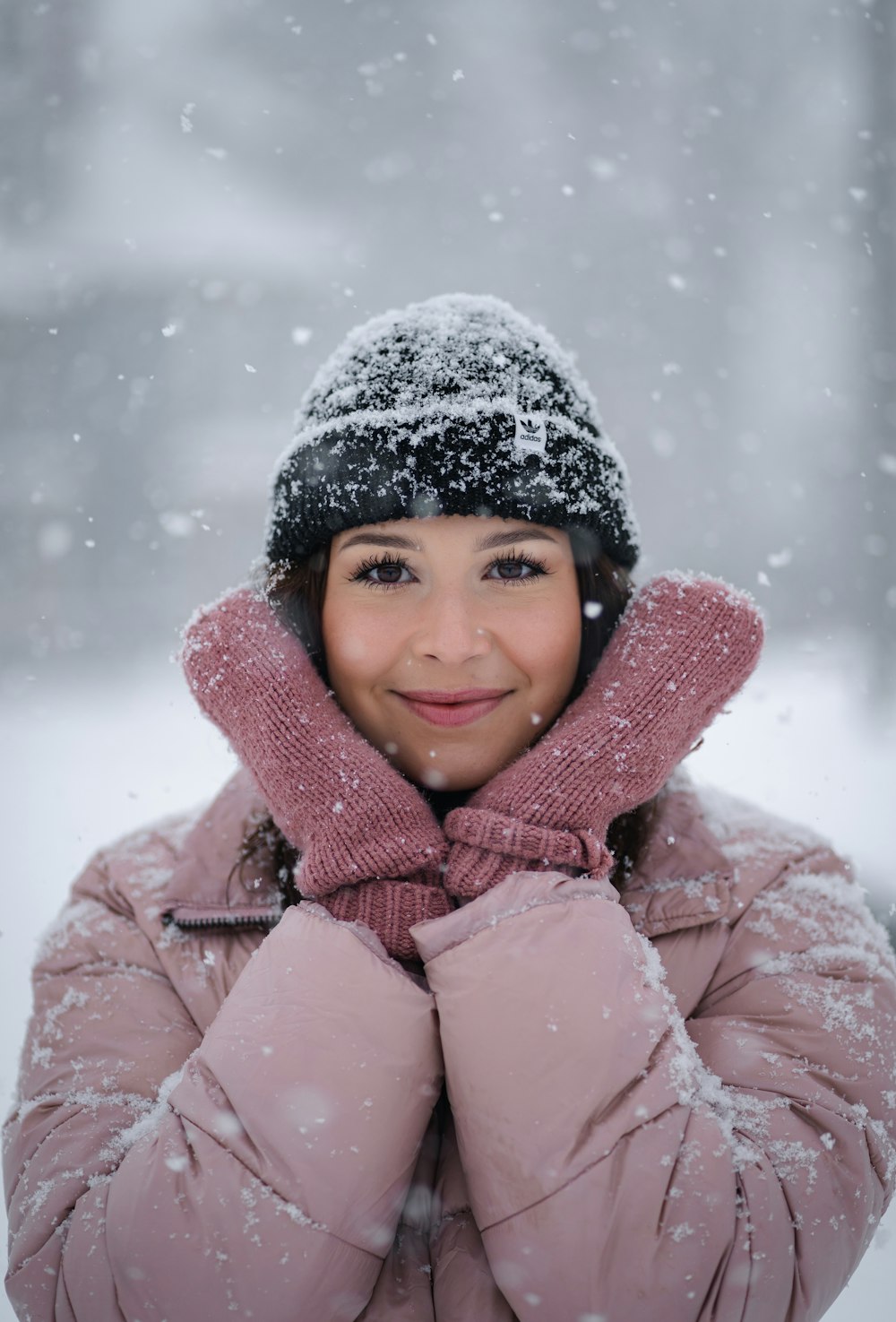 a woman wearing a pink coat and a black hat in the snow