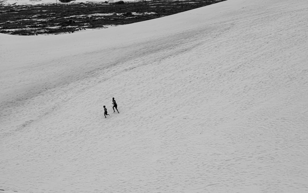 a couple of people standing on top of a snow covered slope