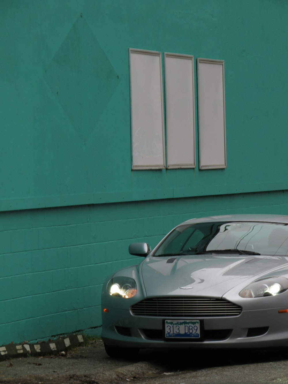 a silver sports car parked in front of a green building