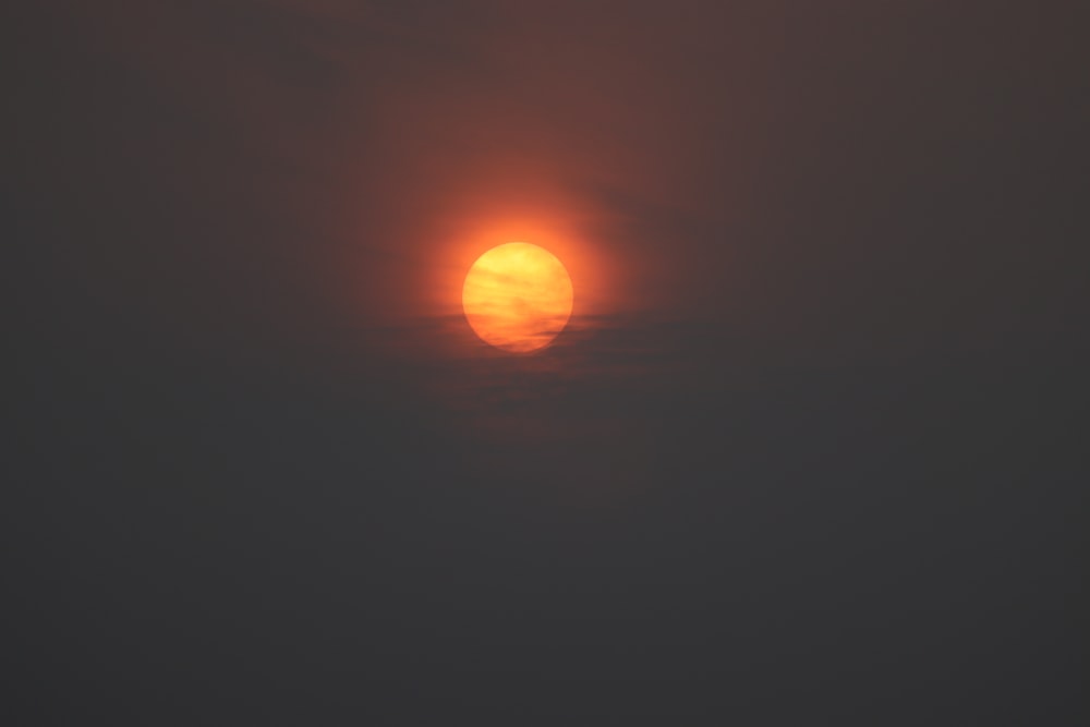 the sun is setting in the foggy sky
