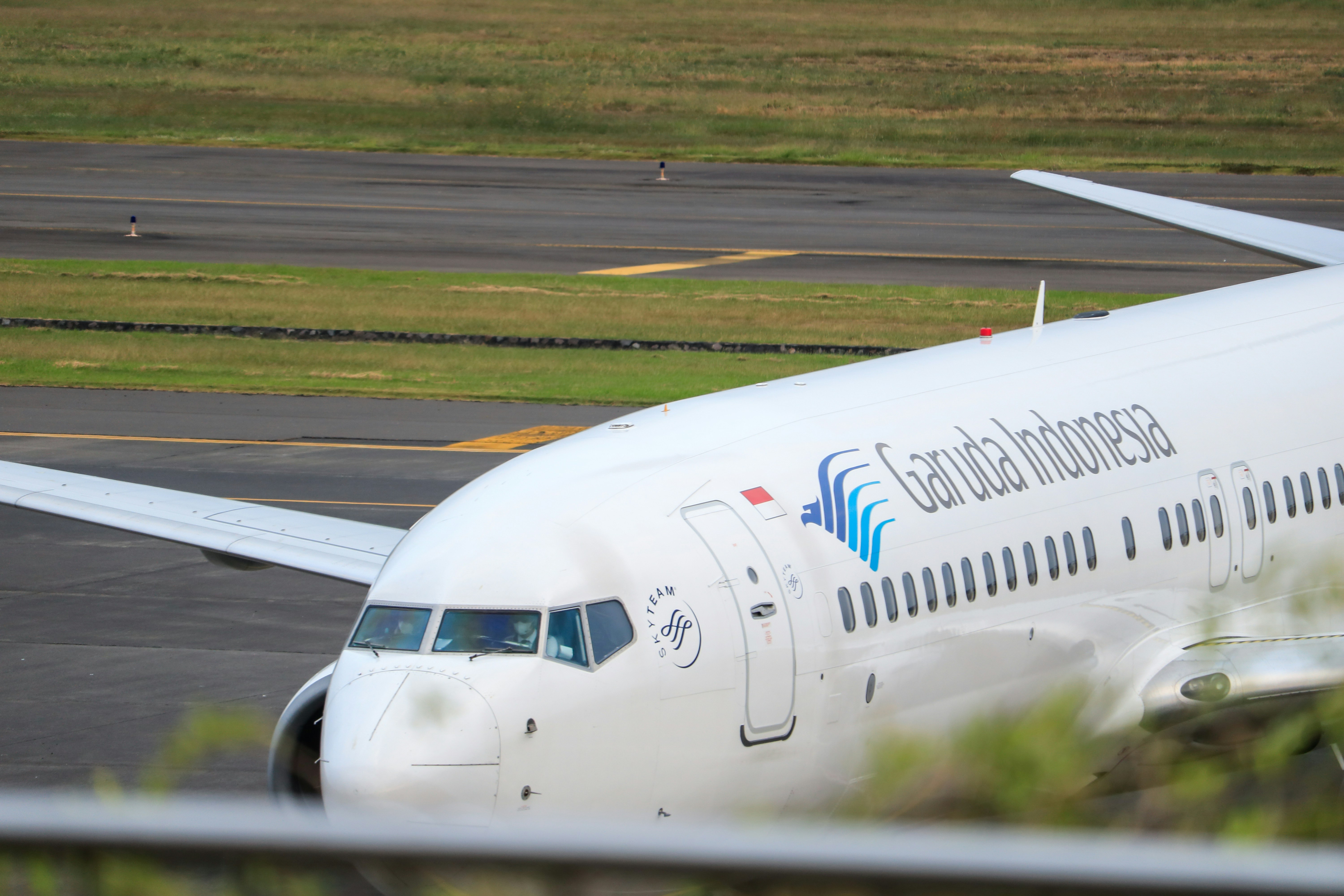 a large passenger jet sitting on top of an airport tarmac, Garuda Indonesia arrived in The Juanda International Airport. The plane will be parked.
