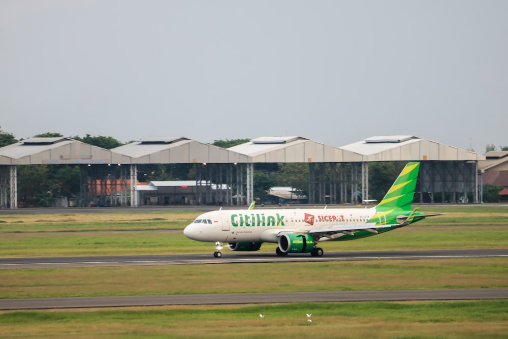 a green and white plane is on the runway