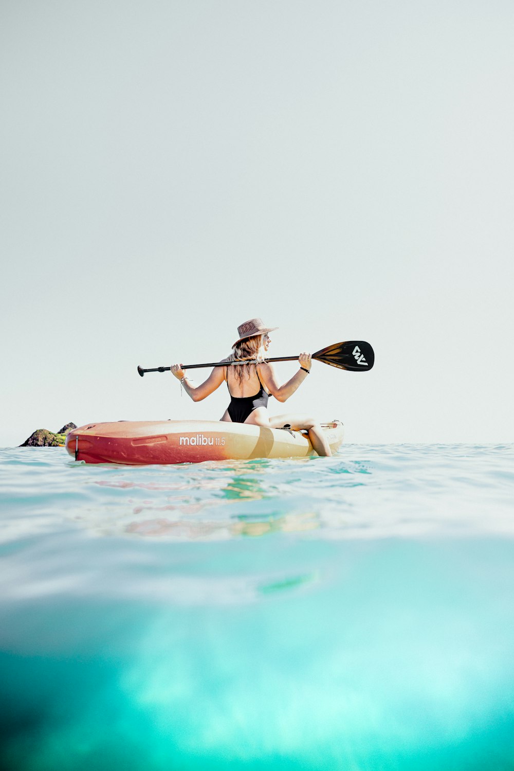 a woman in a bikini paddling a kayak in the ocean