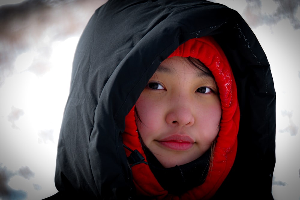 a woman wearing a black and red jacket and a red hood