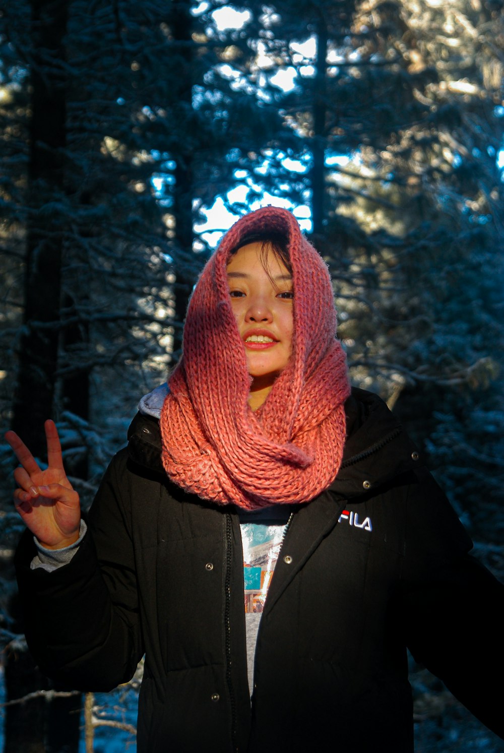 a woman wearing a pink scarf standing in the woods